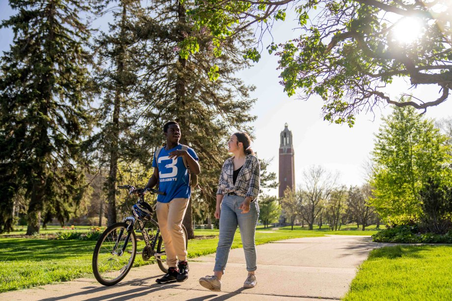 Two students walking and biking on campus
