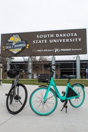 A teal and black bike outside underneath the SDSU stadium sign.
