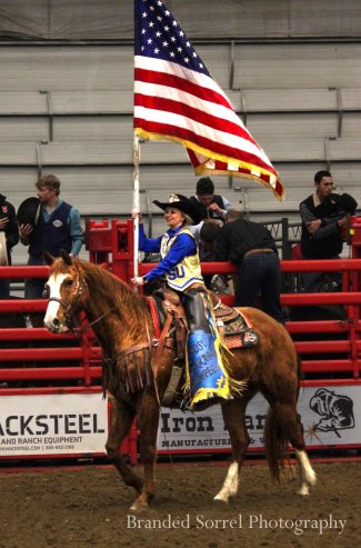 Elle Pieper, ambassador, riding horse and carrying the American Flag at the Jackrabbit Stampede.