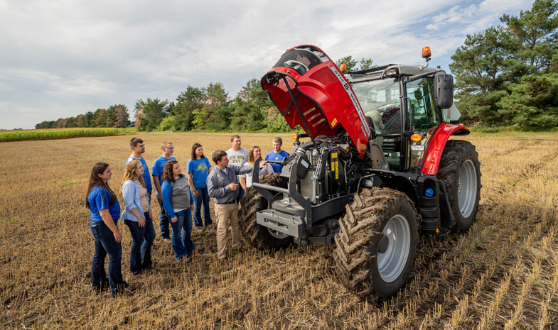 students and instructor in the field with a tractor