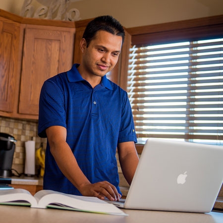 Male student working at his computer in his kitchen