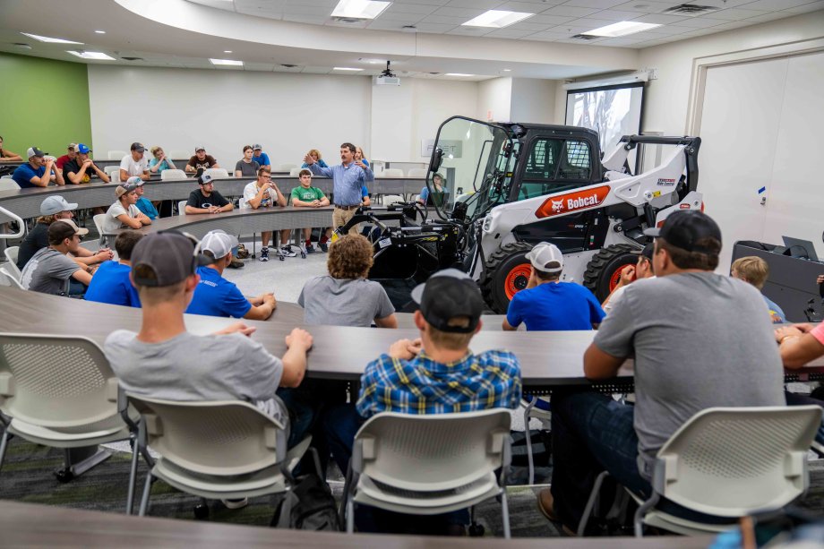 students in classroom in raven precision agriculture center with a bobcat skid steer