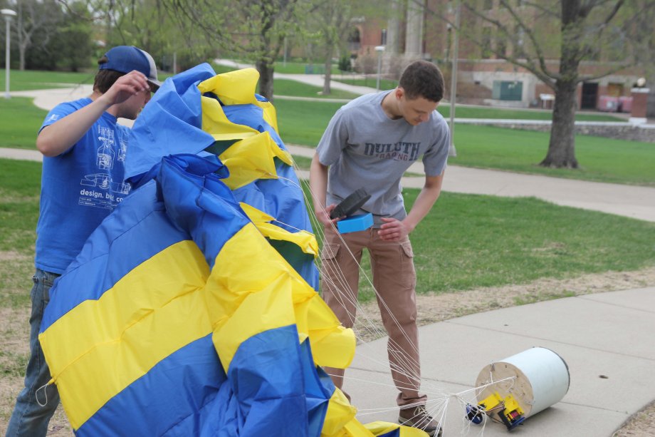 Ben Brainard wrestles with the parasail as Brayden Crawford examine the Project Jack Drop container after it was dropped from the Campanile May 10.