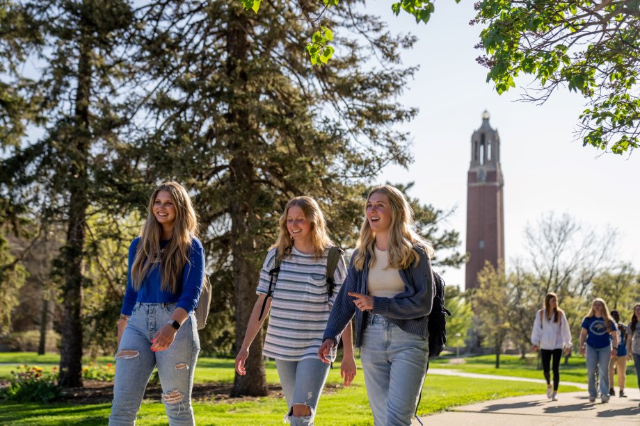 Three students walking on campus near the campanile