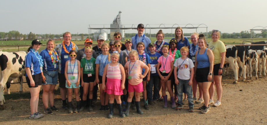 Dairy camp 2023 participants standing in a field with cows.