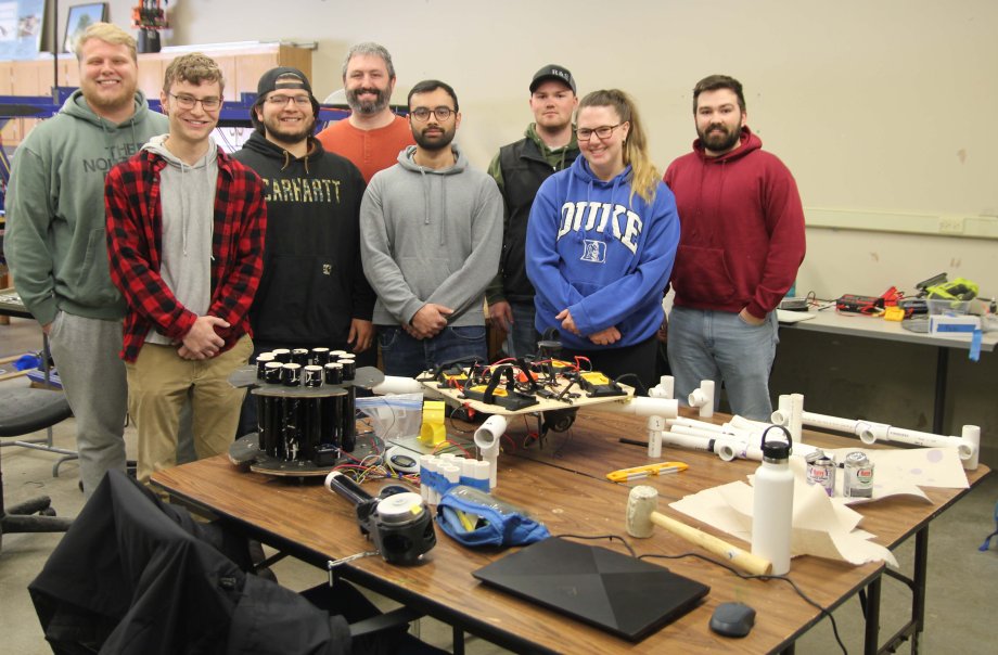 Members of the drone and seed pod dispensing team gather around their "in-progress" unit. Pictured, front row, from left, are Trevor Brezen, Daniela Khurram and Alison Hall. Back row, Cole Hulstein, Cris Hernandez, Adam Breuer, Landon Schulte and Justin Clarke. Not pictured is John Harmon.