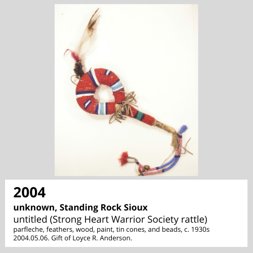 unknown artist, Standing Rock Indian Reservation untitled (Strong Heart Warrior Society rattle) parfleche, feathers, wood, paint, tin cones, and beads, c. 1930s South Dakota Art Museum Collection. 2004.05.06. Gift of Loyce R. Anderson.