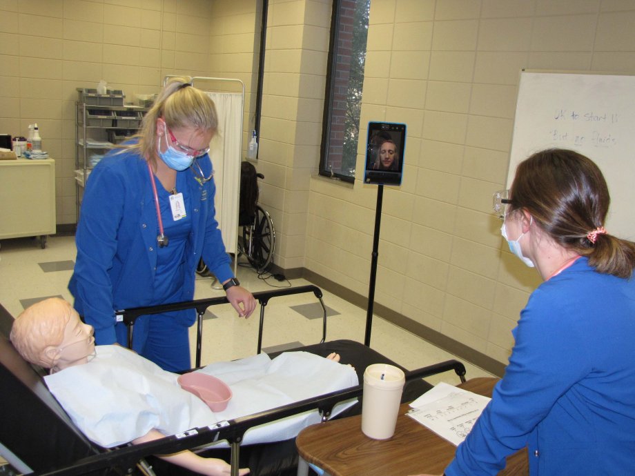 Hailey Olson, left, of Sioux Falls, and Jordan Neubrand, of Sioux City, Iowa, attend a patient mannequin in the simulation lab on the Brookings campus Oct. 27. The second-semester nursing students are observed by instructor Nicole Carlson, who was able to participate thanks to a new telepresence robot despite being quarantined at home in Sioux Falls.