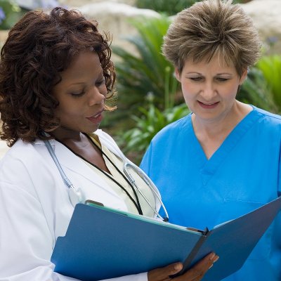 Nurse talking to a doctor while reviewing a chart.