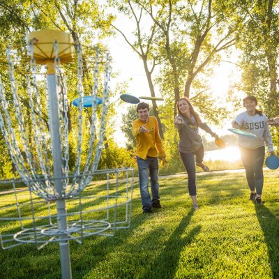 four students playing frisbee golf