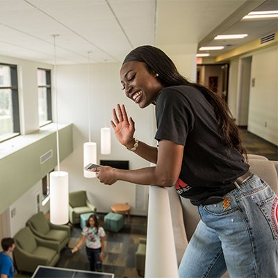 Student waving to others in a lobby