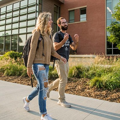 Two students walking by the AME building
