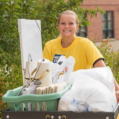 Meet State volunteer carrying a student's belongings to their residence hall