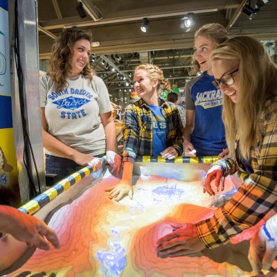 Four students interacting with the weather exhibit.