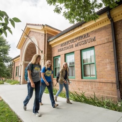 Three female students walking in front of the South Dakota Agricultural Heritage Museum.