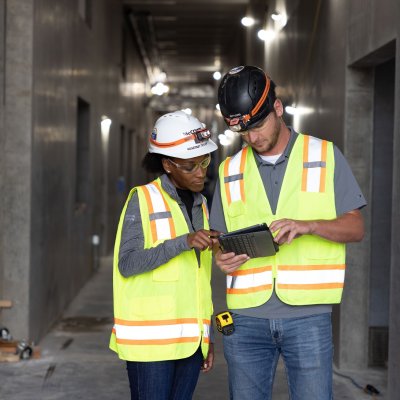 Individuals standing in construction area looking at a tablet.