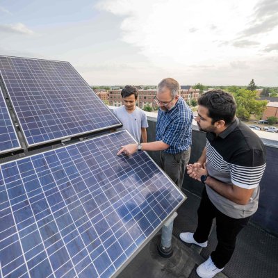 Two students and a professor looking at a solar panel array.