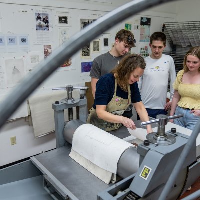 Three students and instructor in a printmaking lab.