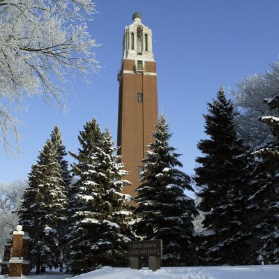 Coughlin Campanile with snow on the ground and evergreen trees.