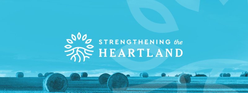 Strengthening the Heartland Logo overlaying a blue toned image of a field of bales