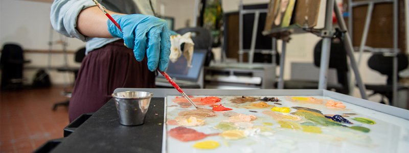 image of a hand mixing paints on a pallette