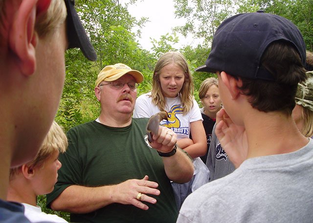 Instructor holding a cedar waxwing surrounded by students