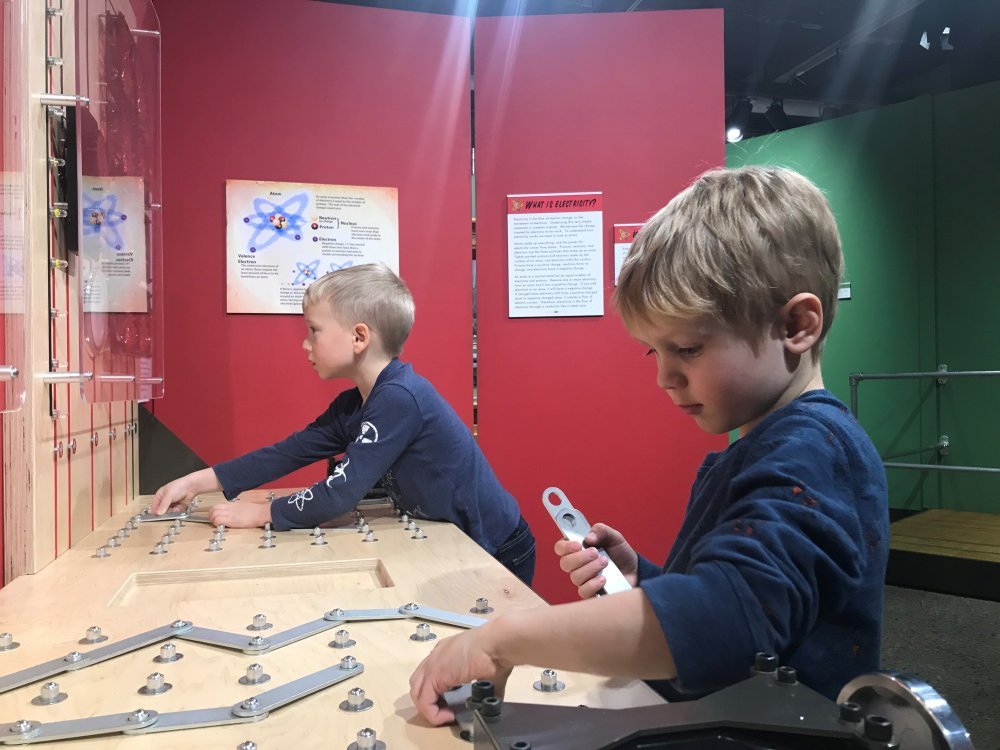 Two boys play with an interactive exhibit piece.