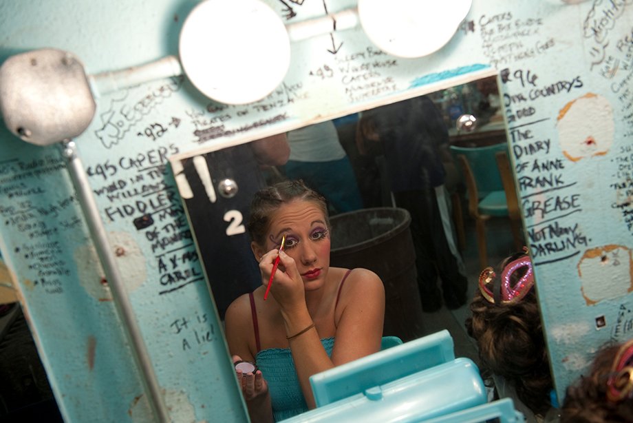 Theater student applying makeup backstage