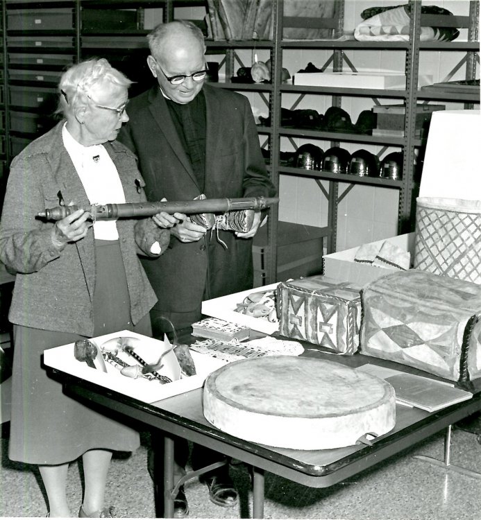 Rev. Frank M. and Abigail Thorburn review pieces from their collection of American Indian objects, 1986. Amelia Iron Necklace’s beaded hymnal cover sits on the table in front of them. 