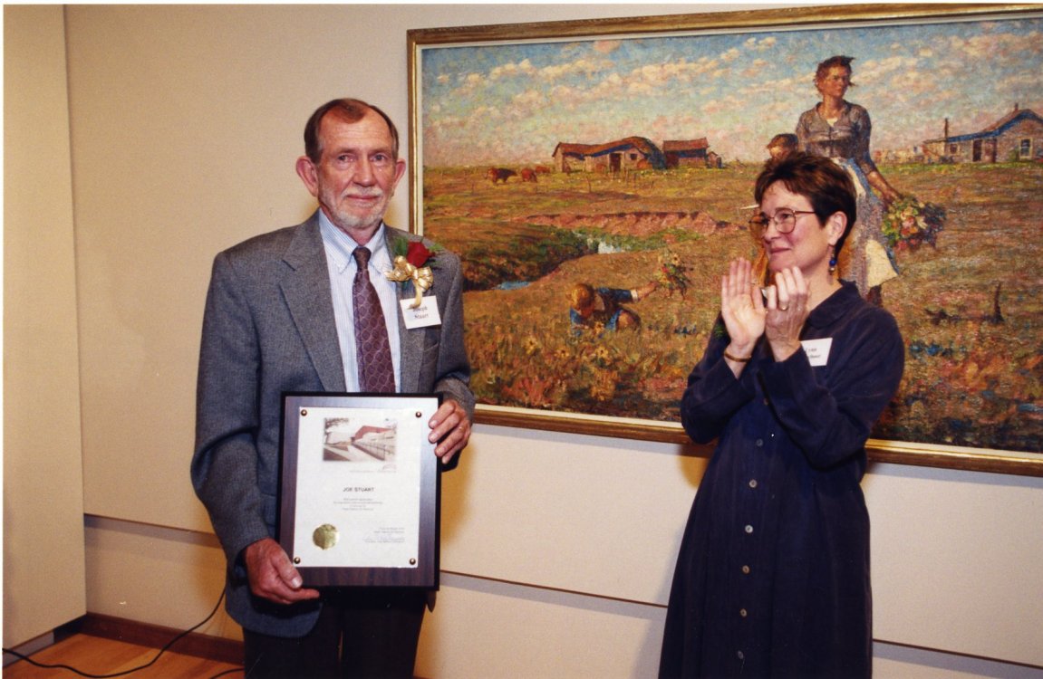 Joseph M. Stuart, Director of the South Dakota Art Museum from 1971-1993, receives a plaque from Lynn Verschoor at the Museum’s rededication in December 2000. 