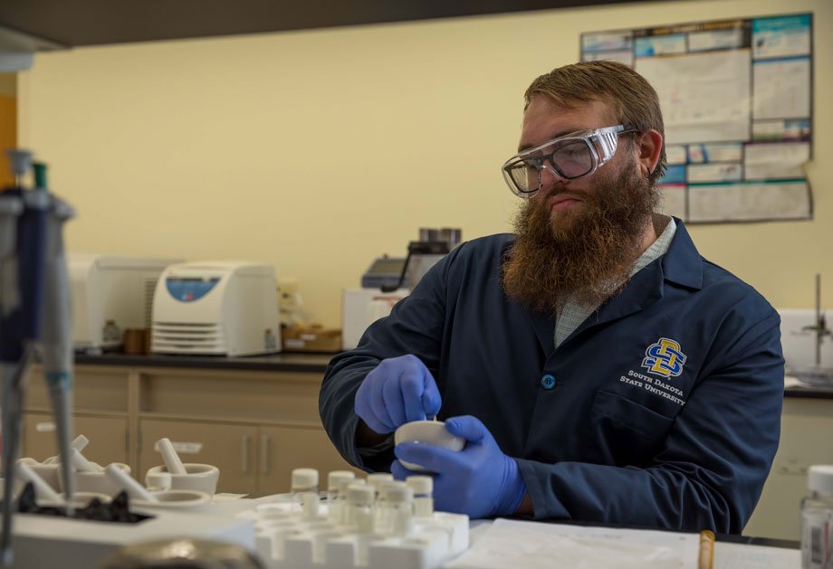 Doctoral student Kyl Burch grinds aspirin using mortar and pestal