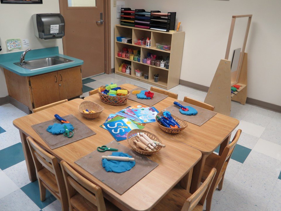 This table has play dough with a variety of accessories and tools.