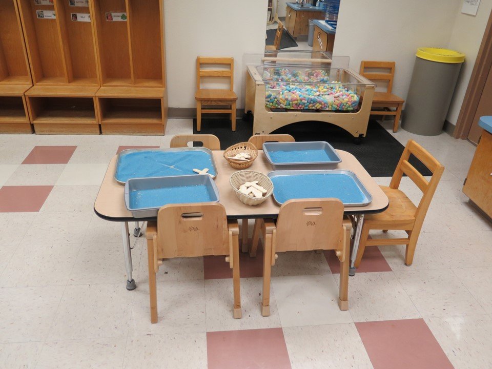 Toddler classroom table with sand sensory trays.