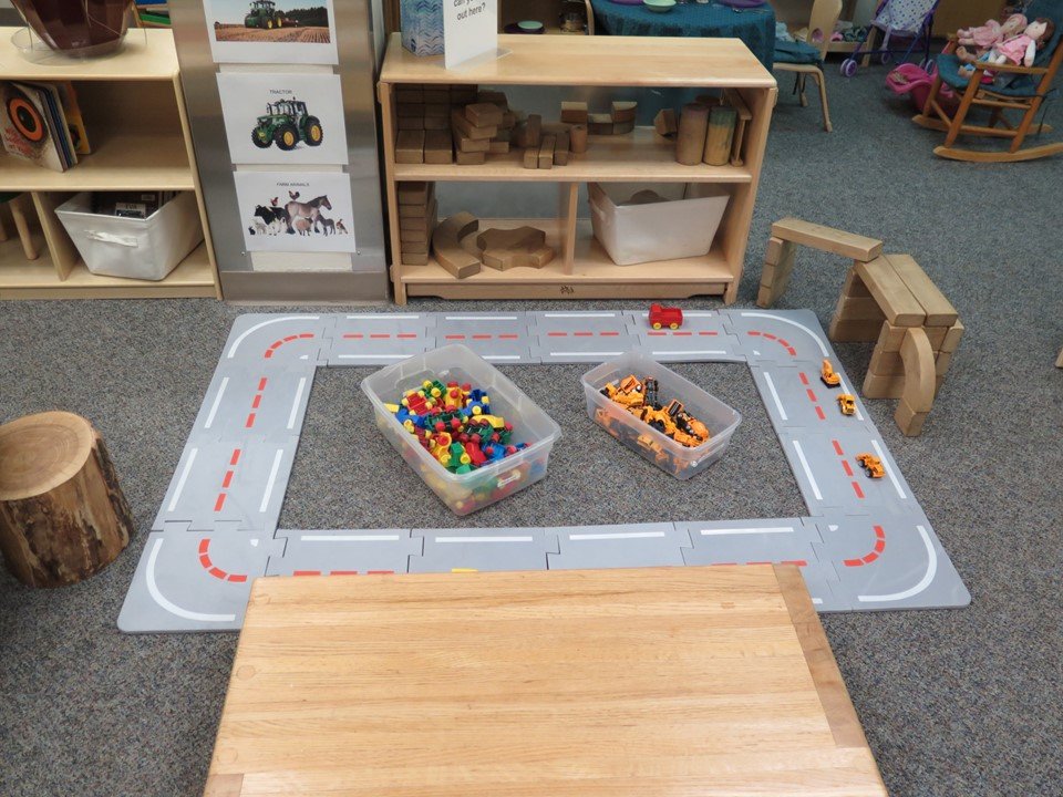 Toddler block area with cars and road mat.