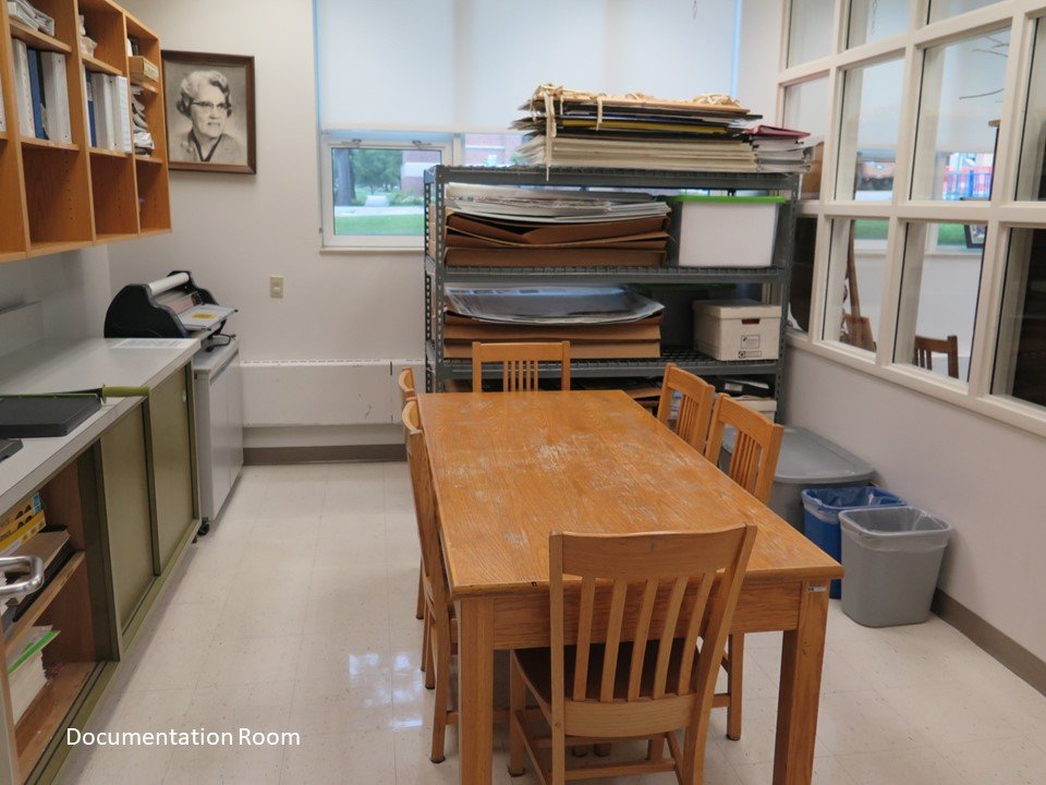 A documentation room that contains archived program documents and projects. It also includes a table with chairs. 