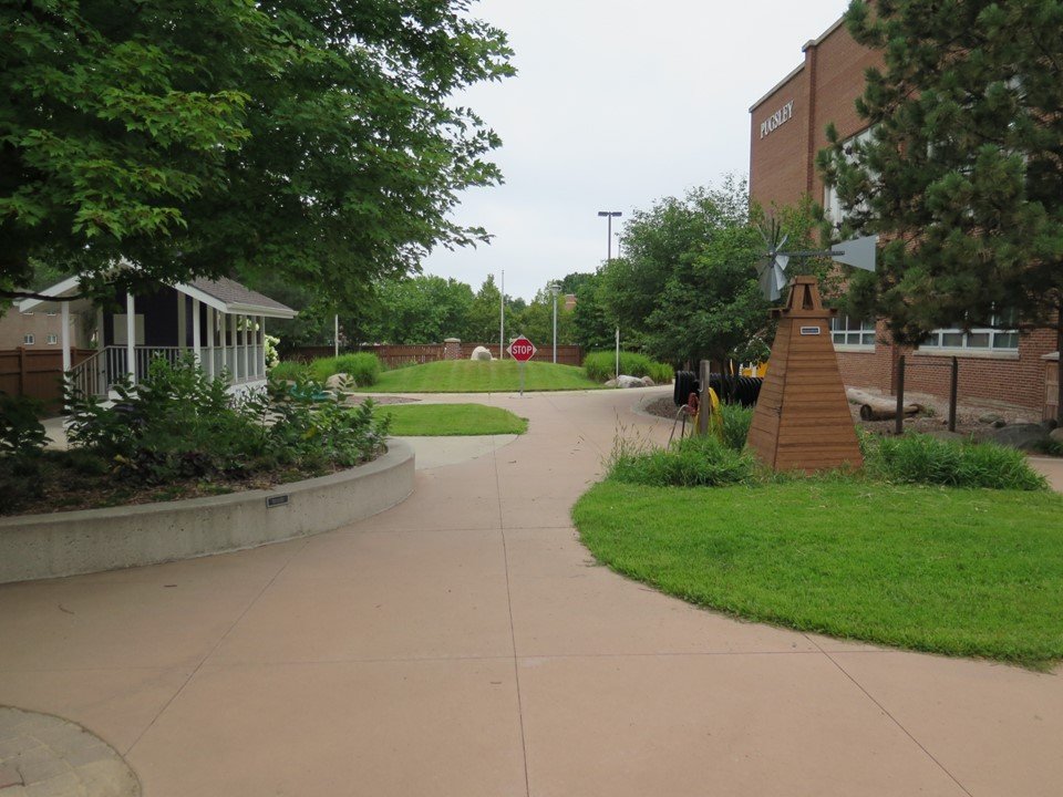 View of the playground showing the length of the space. Includes the windmill and raised gardens.
