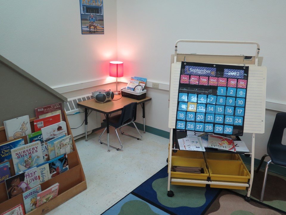 In the Kindergarten classroom there is a teaching easel, bookcase with books and a listening station.