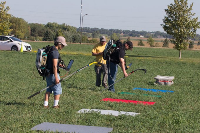 Calibration teams using instruments positied over different colored squares in a field