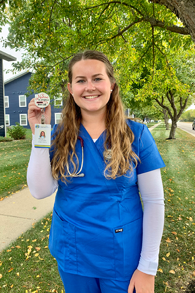 Hannah Ference stands by a tree holing her badge for clinical