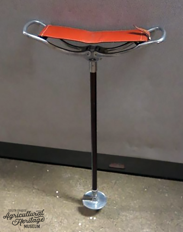 Opened "shooting stick" or folding chair with a red leather seat.