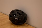 Black bike helmet against a white wall