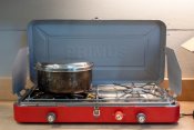 Red camping stove with pot on burner
