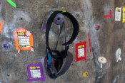 Black rock climbing harness hanging on a rock wall