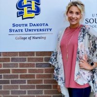 Brooke in front of South Dakota State University College of Nursing logo sign