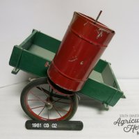 SDAHM Collection, 1981:003:002.  Red cylindrical bin attached to a green square structure.  The green wooden base is attached to two wheels.