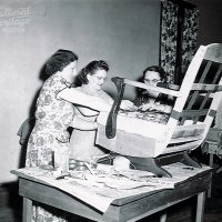 Black and white photo of three women reupholstering a chair.