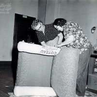 Black and white photo of two women reupholstering a chair.