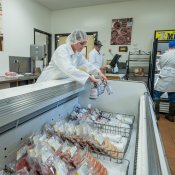 Workers placing meat in the cooler at the SDSU Meat Lab.
