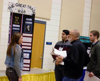"NHD in SD Judges speaking with a student about her exhibit board titled, "The Great Trade War.""