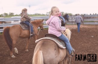 Young girls riding horses on a ranch.